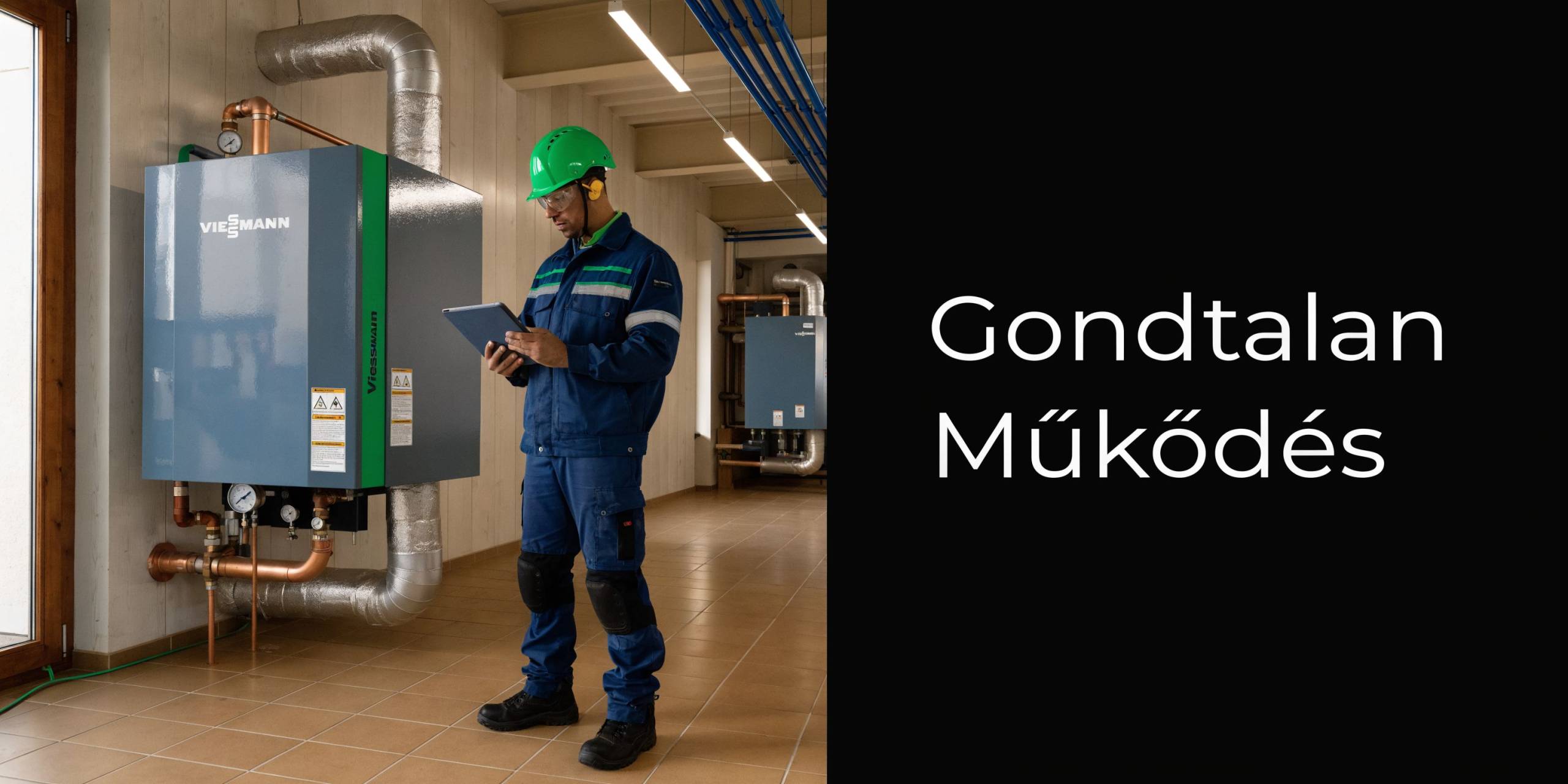 Szerelő egy Viessmann ipari kazán mellett, miközben tableten ellenőrzi a rendszer gondtalan és hatékony működését.